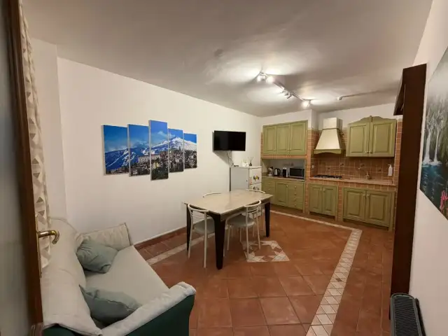 Zona giorno di EtnAmore con tavolo, divano e cucina